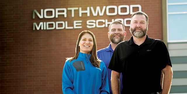 Three people standing in front of Northwood Middle School