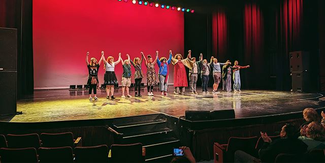 Group of performers take a bow on stage