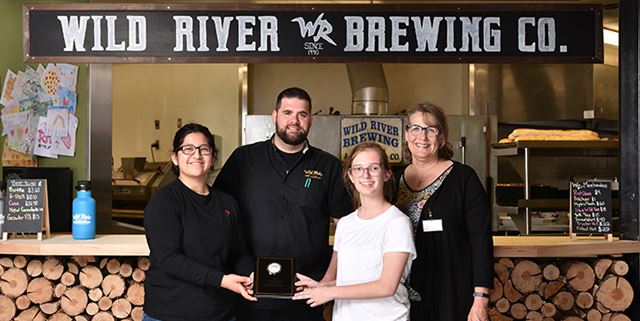 Deaf and Hard of Hearing Academic Bowl participants smiling and posing with award at Wild River Pizza
