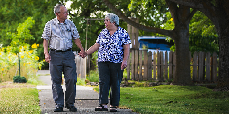 Man and woman holding hands on a walk outside on sidewalk