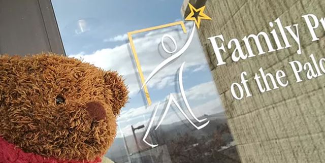 Teddy bear in front of Family Promise of Palouse logo