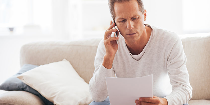 Concerned man talking on phone looking at paper