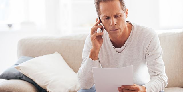 Concerned man talking on phone looking at paper