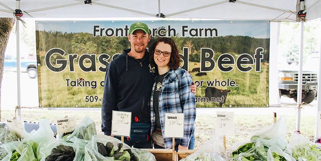 Man and woman standing at farmers market booth