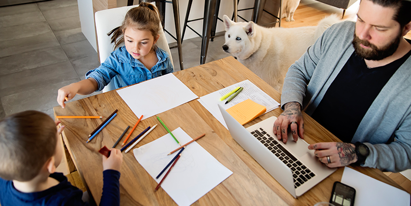Dad on laptop sitting at table with children