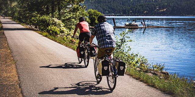 Two people riding bikes on a trail next to Lake Coeur d'Alene