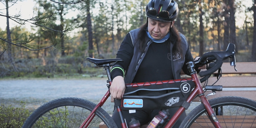 Man showing his homemade bike bag on his bike while wearing bike gear outdoors