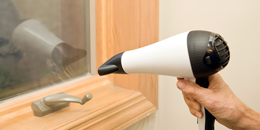 Sealing window drafts with a hair dryer and heat shrinking plastic window film insulation