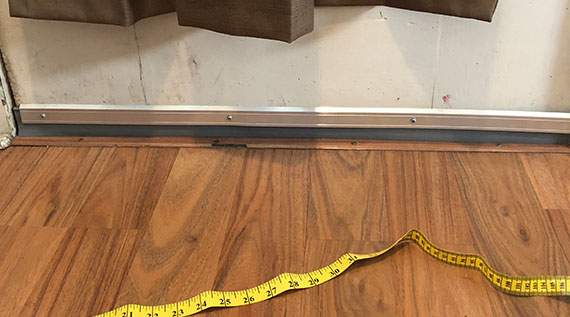 Door sweep on bottom of door with a tape measure on the floor in front of it