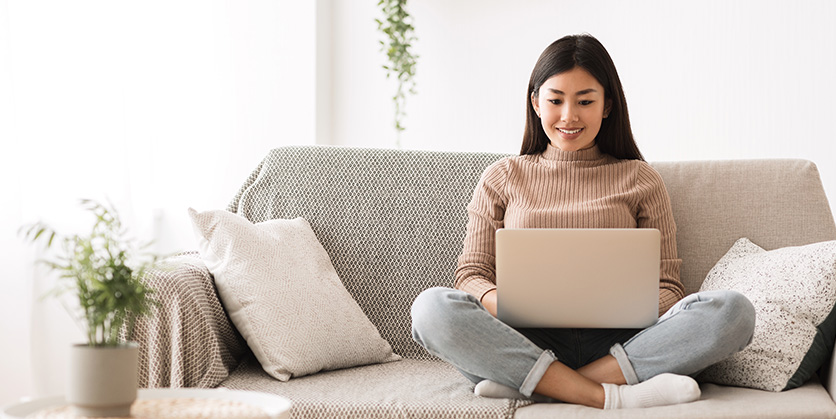 Woman sitting on couch and looking at laptop