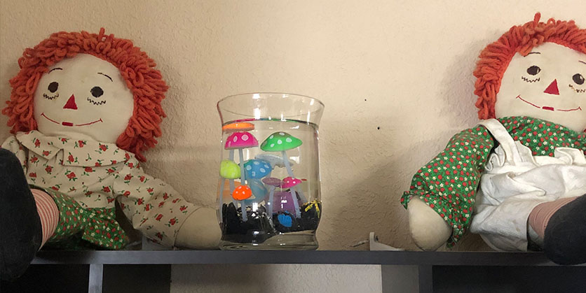 Vase filled with water and plastic glow in the dark plants on a table