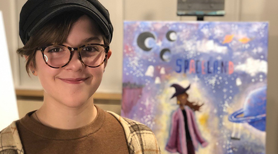 Girl smiling in front of a painting she has painted