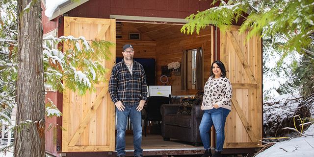 Man and woman standing outside of a shed that has been converted to a comfortable office for remote work