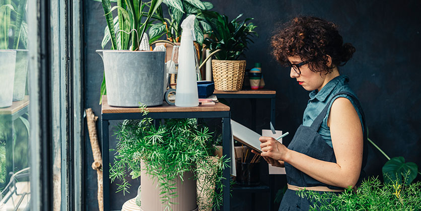 Florist writing notes about her plants at her shop