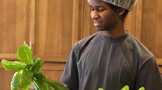 Man holds up a head of lettuce he has grown