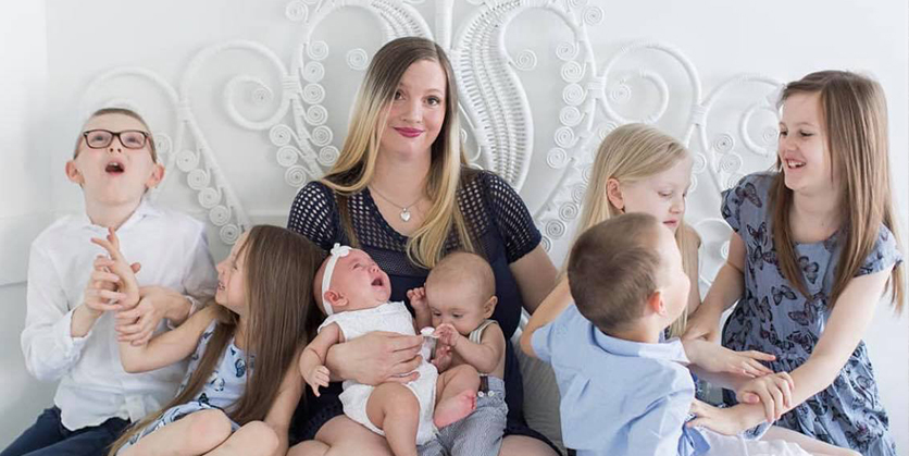 Woman smiling while sitting surrounded by her 7 children