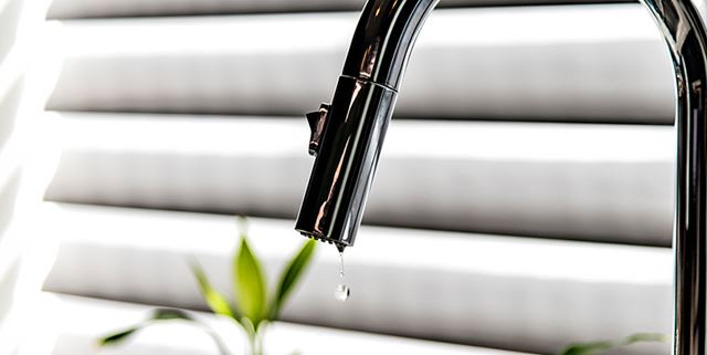 A drop of water falling into a kitchen sink from a leaky faucet