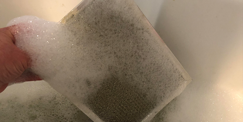 Range hood in soapy water being cleaned