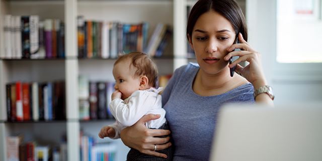 Worried mother on the phone, looking at her laptop while holding her baby