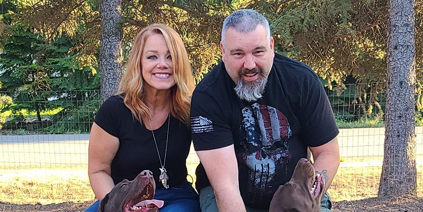 Man and woman smiling for the camera with two dogs sitting at their feet