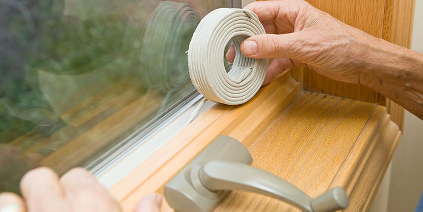 Closeup of hands applying rope caulk to window