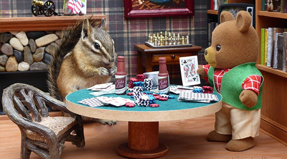 Chipmunk sitting at a tiny poker table with a teddy bear