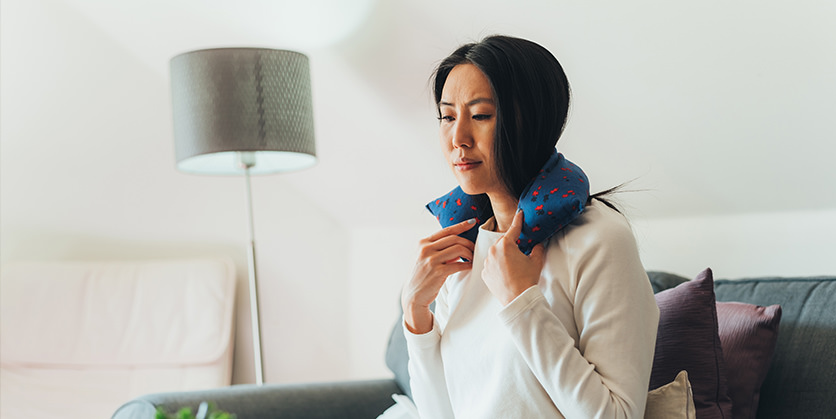Woman in a long sleeve shirt with a DIY rice heating pad on her neck