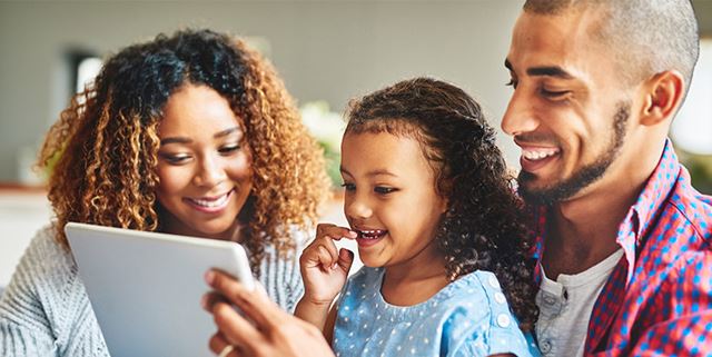 Mother, father and daughter looking at a tablet together and smiling