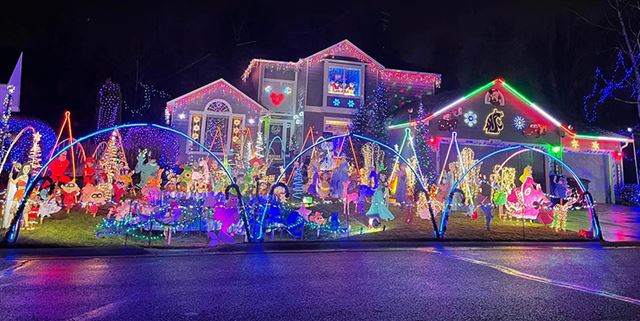 At night, a house with many holiday decorations and lights, many of which are Disney decorations