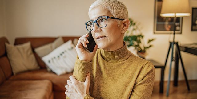 Senior woman on phone in living room looking concerned