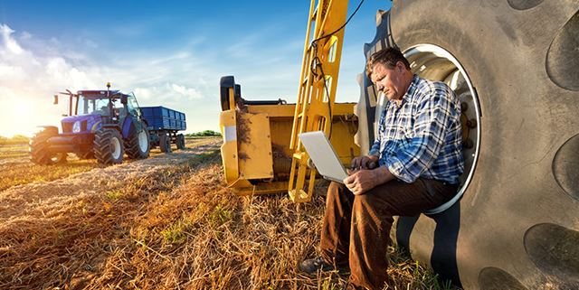 Farmer man looks at laptop while in a field