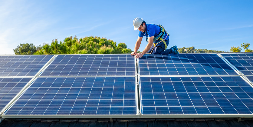 Man installing solar panels on roof
