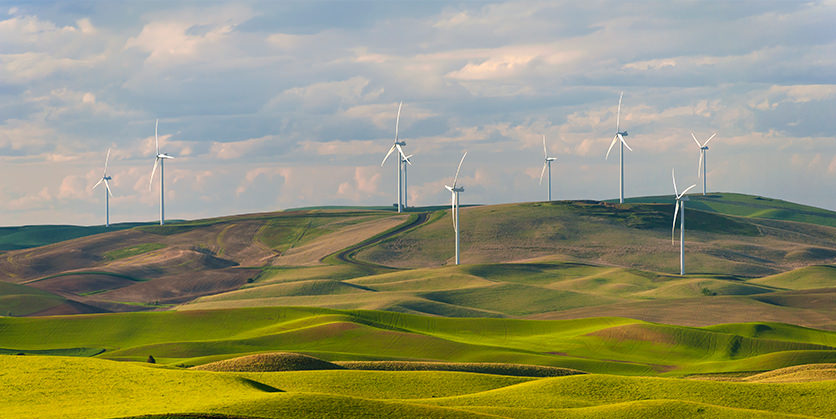 Windmills on green hills in front of a cloudy sky
