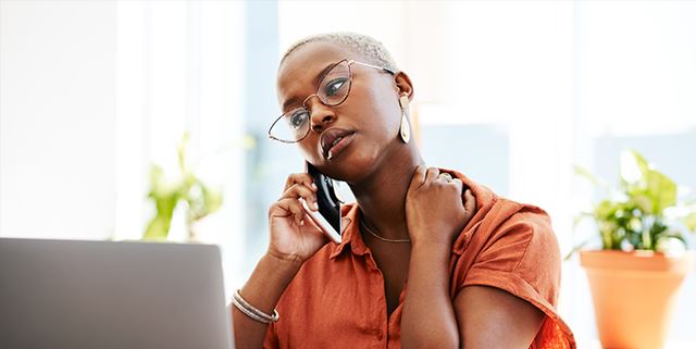 Woman in front of her laptop, looking stressed while on the phone