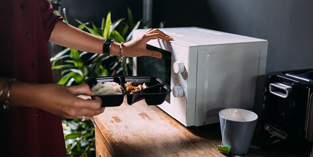 Closeup of someone putting food in a microwave to reheat