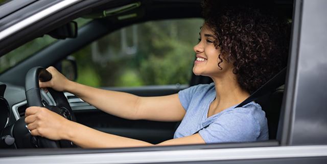 Young woman smiling while driving a car