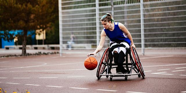 Woman in wheelchair playing basketball outdoors