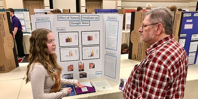 Young woman talking to a man about her project at a science fair