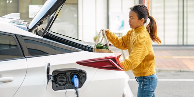 Woman loads groceries into electric vehicle