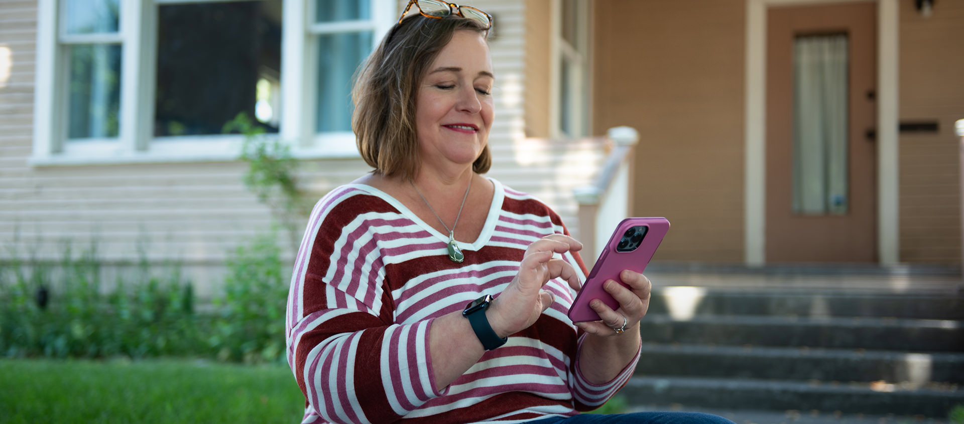 An Avista customer looking at her mobile phone outside her home