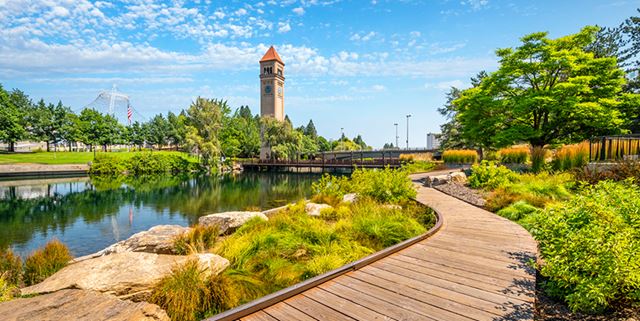 Clocktower at Riverfront Park, Spokane with a blue sky, greenery, and the river