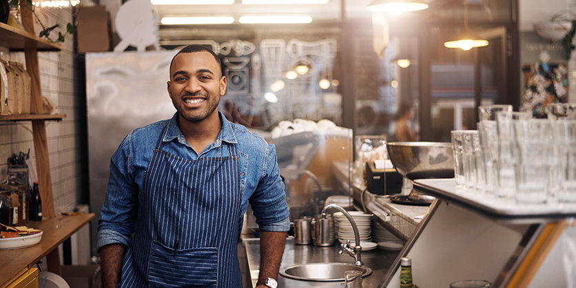 Café employee smiling behind the counter at work.