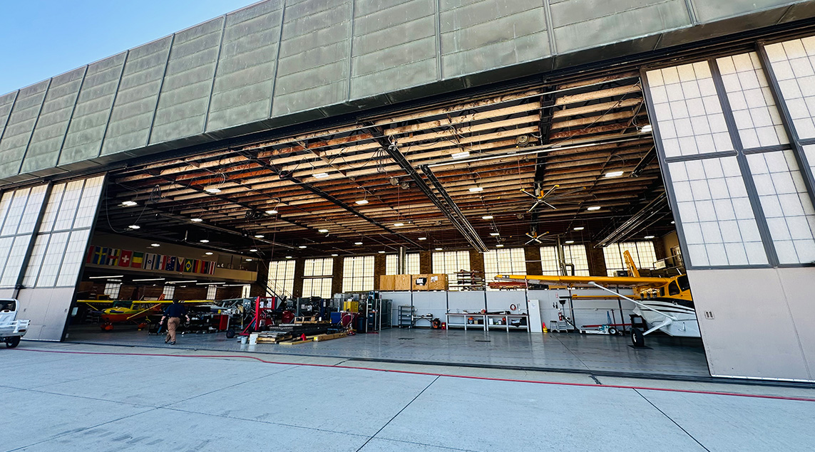 Open aircraft hangar with LED lights inside.