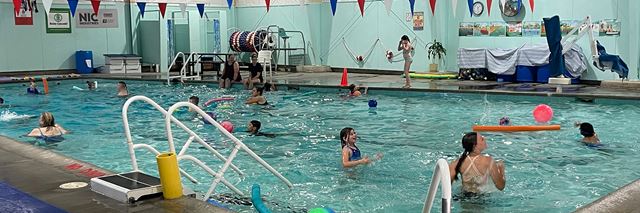People swim and play in an indoor community pool.