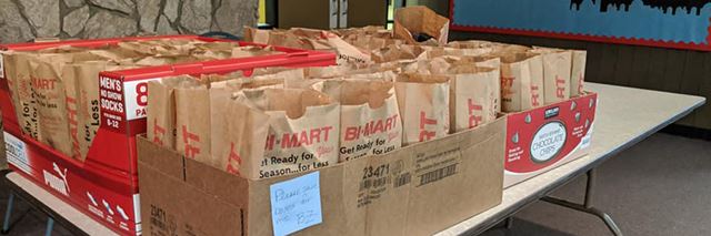 Many paper bags in boxes on a table.