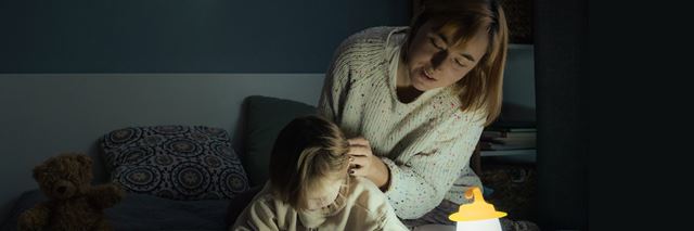 Mother and daughter at home in the dark with a battery operated lantern.