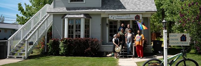 A group of people stand on the porch of Sand Creek Connections Clubhouse.