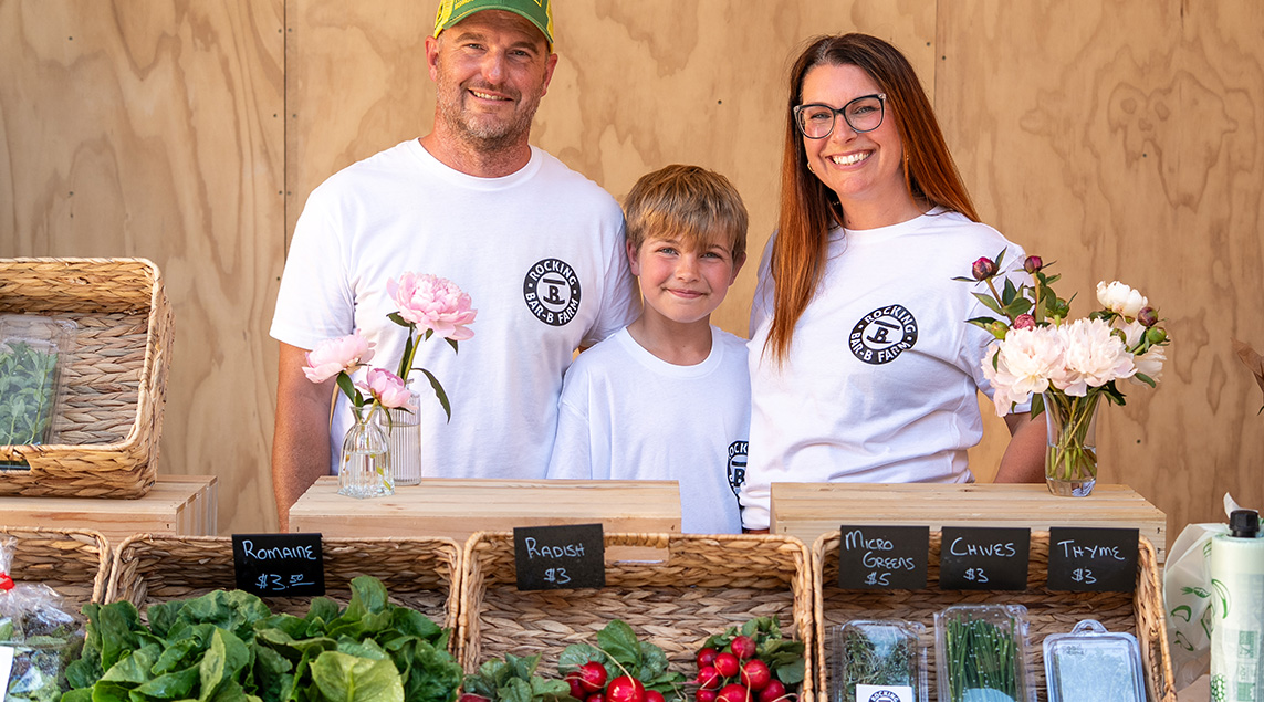 Rocking Bar-B Farm poses for a photo at their outdoor vegetable stand at Scale House Market. 