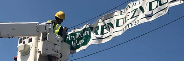 Person in bucket truck hangs Rendezvous Days sign.