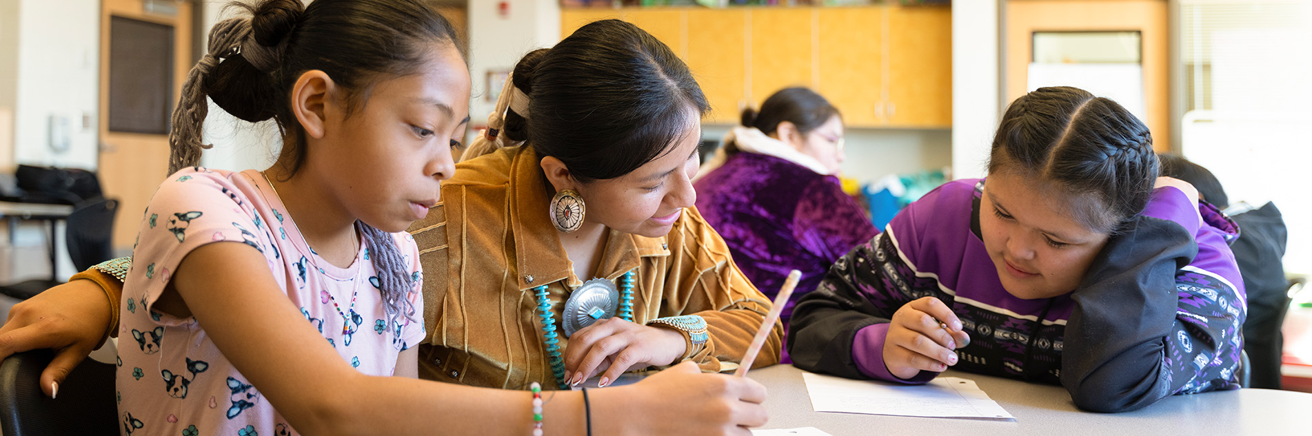 Teacher helping two students with their work at school.